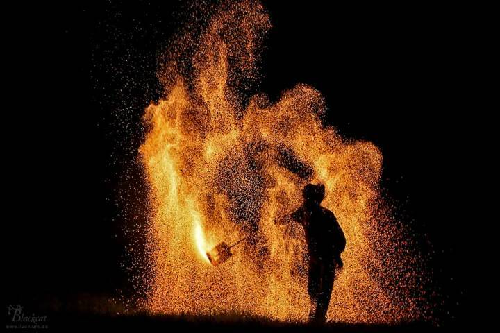 Ein Mann steht inmitten eines Glutregens während einer professionellen Feuershow