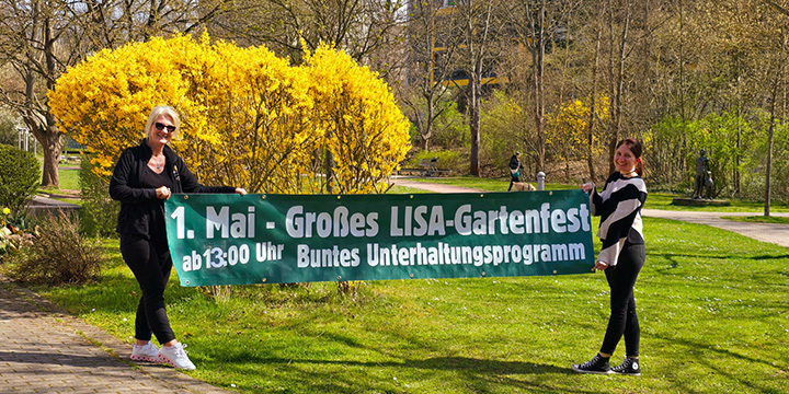 Zwei Frauen. die Betreiberin von Simis Restaurant und die Veranstaltungsorganisatorin des LISA halten ein Werbebanner für das Gartenfest hoch.  ©JenaKultur