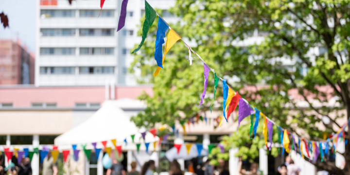 Bunte Wimpel im Vordergrund und im Hintergrund das Gebäude des Stadtteilzentrum LISA mit Garten und Fest zum 1. Mai  ©JenaKultur, C. Worsch