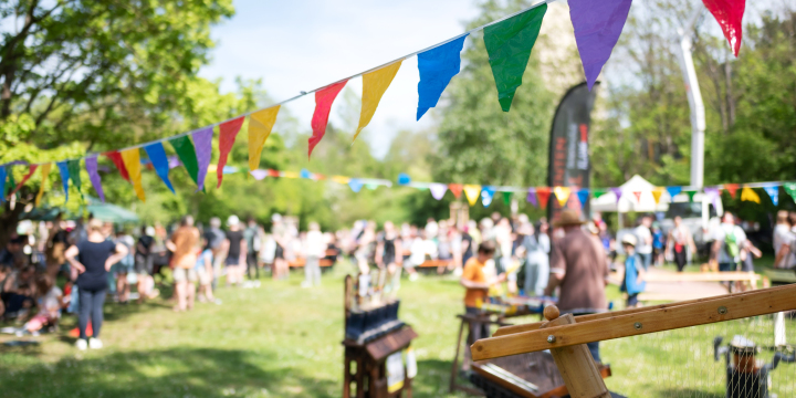 Wimpel hängen im Vordergrund und eine Festszenarie ist im Hintergrund verschwommen erkennbar.  ©JenaKultur, C. Worsch
