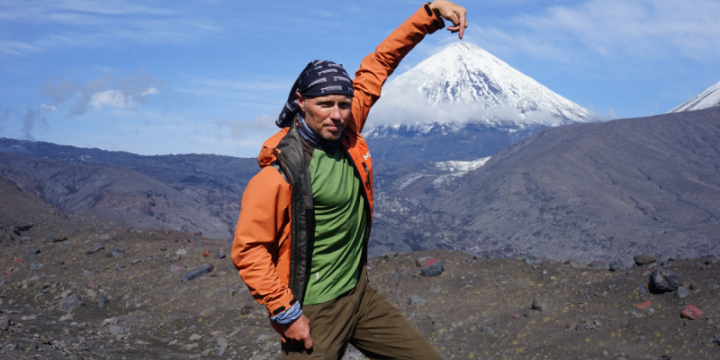 Der Wanderer Ralf Schwan vor dem Berg Kljuschewskaja Sopka in der Russischen Wildnis. Er hält seinen Finger so, dass es aussieht als würde er die Spitze von antippen und dem Berg so einen festen Halt geben.